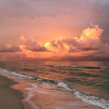 the sun is setting over the ocean with clouds in the sky and waves on the beach