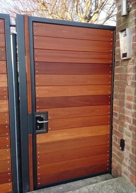 a pair of wooden doors in front of a brick wall with metal bars on the sides