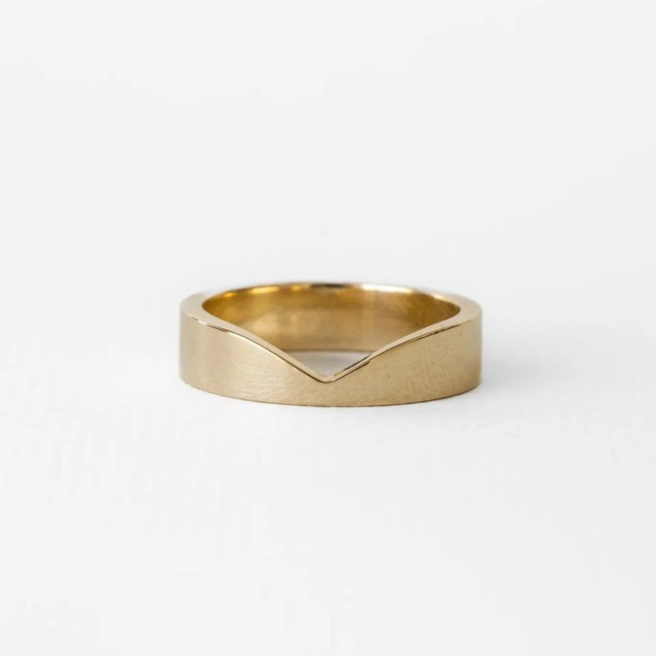 a gold wedding band with an irregular shape on the side, and a curved edge