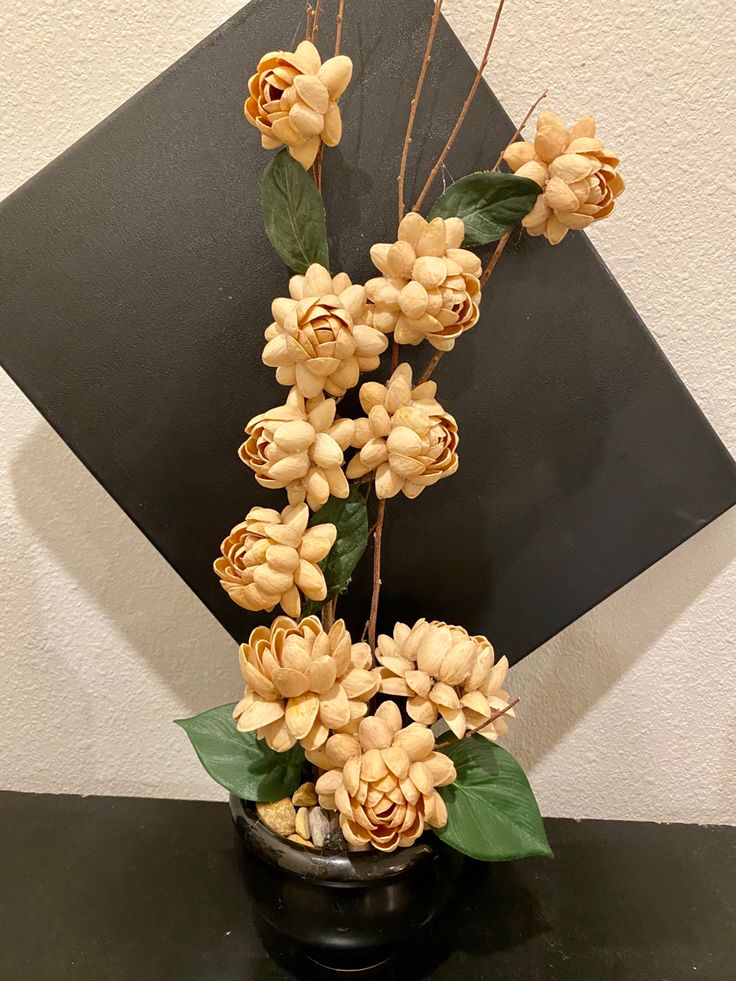 a vase with some flowers in it sitting on a black table next to a wall