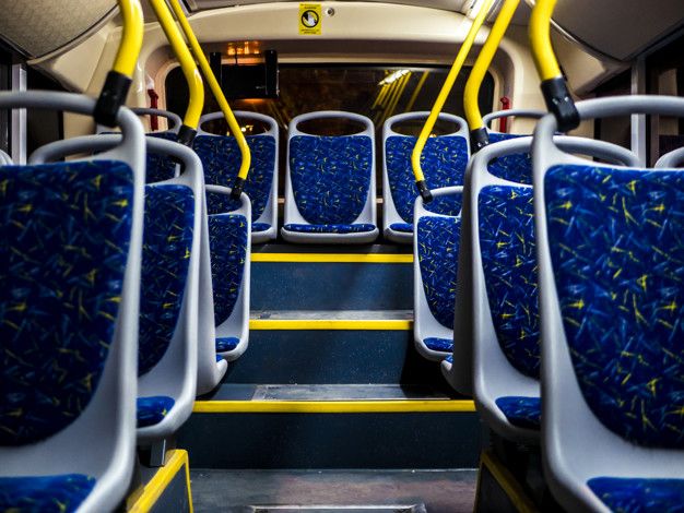 an empty bus with blue seats and yellow handles