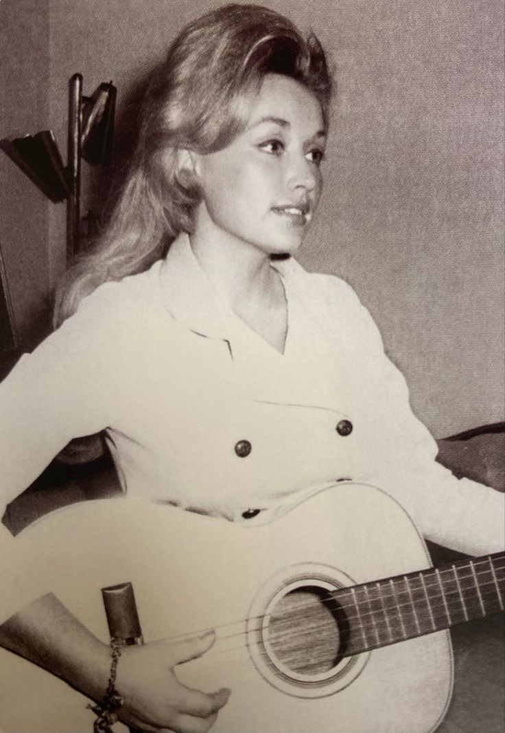 a black and white photo of a woman holding a guitar