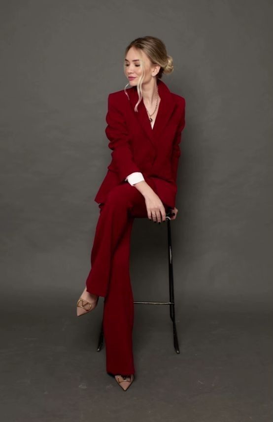 a woman in a red suit sitting on a chair