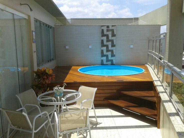 an above ground swimming pool in the middle of a deck with chairs and tables around it