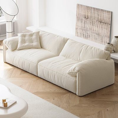 a living room with white furniture and wood flooring, including a large sectional couch