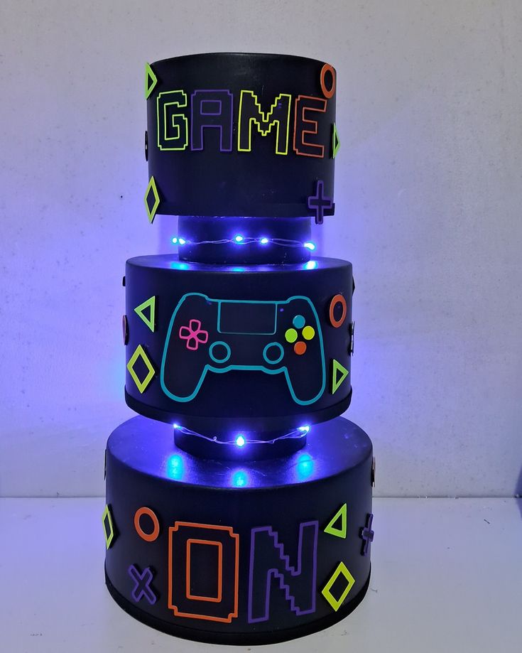 three tiered cake decorated with video game controllers and neon lights on the top layer