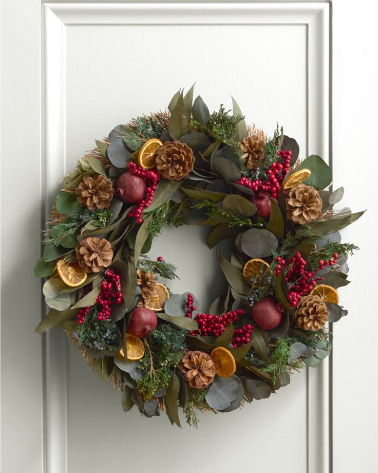 a christmas wreath on the front door with pine cones, berries and other holiday decorations