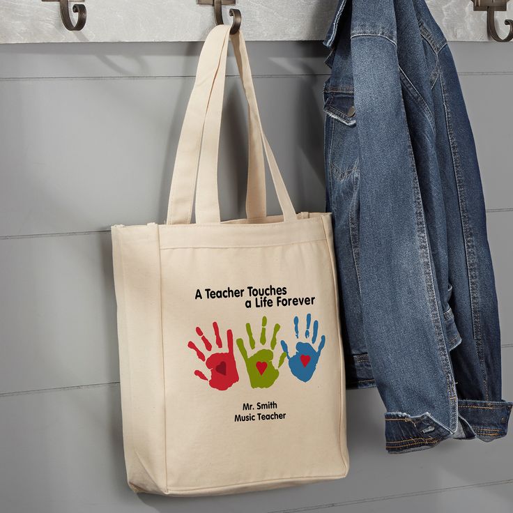 a tote bag hanging on a coat rack next to a pair of denim jeans