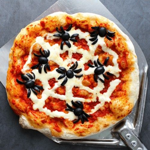 a pizza with black and white toppings sitting on top of a table next to a spatula