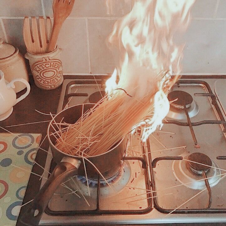 a person is stirring something in a pot on top of the stove with flames coming out of it