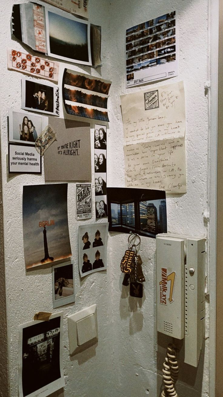 a refrigerator covered in magnets and pictures on the wall next to a telephone booth