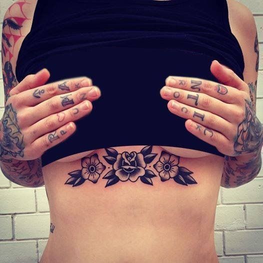 a woman with tattoos on her stomach holding her hands up to her chest and looking at the camera