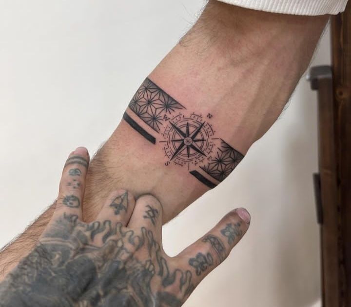 a man's hand with a compass tattoo on it