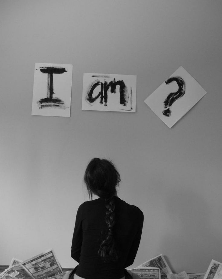 a woman sitting on top of a bed next to papers with letters above her head