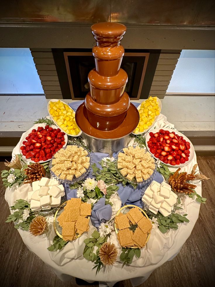 a table topped with a chocolate fountain and lots of desserts on top of it