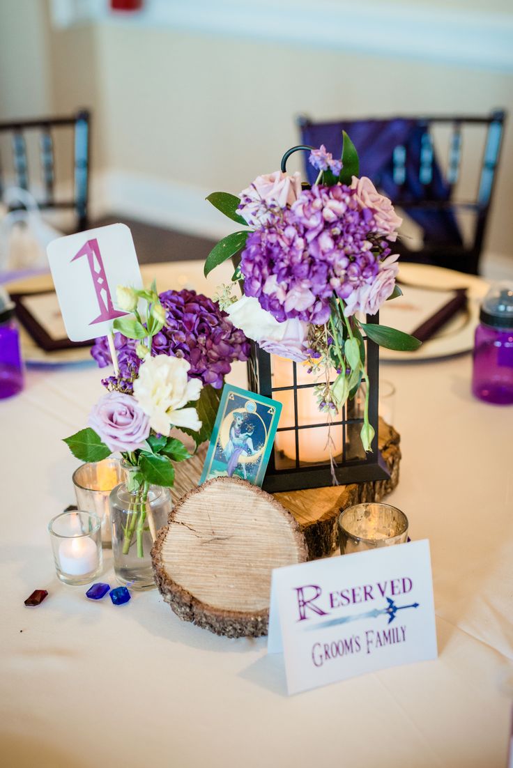 the centerpieces on the table are decorated with purple and white flowers, candles, and cards