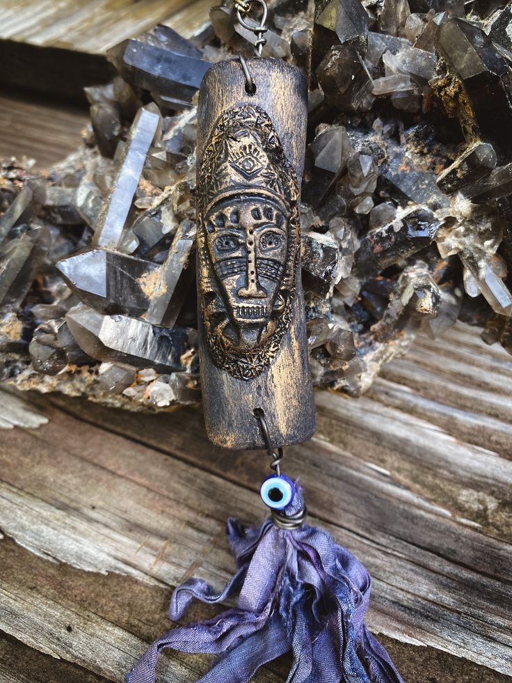 a necklace with an evil eye hanging from it's end on a piece of wood