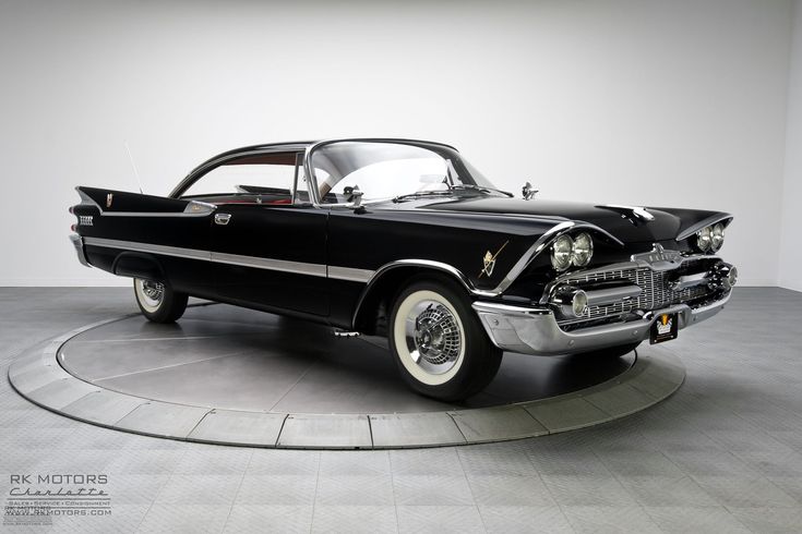 an old black car is on display in a room with white walls and flooring