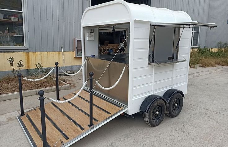 a white trailer with a ramp attached to it's side in front of a building