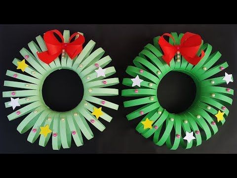 two wreaths made out of green paper with red bows and stars on the sides