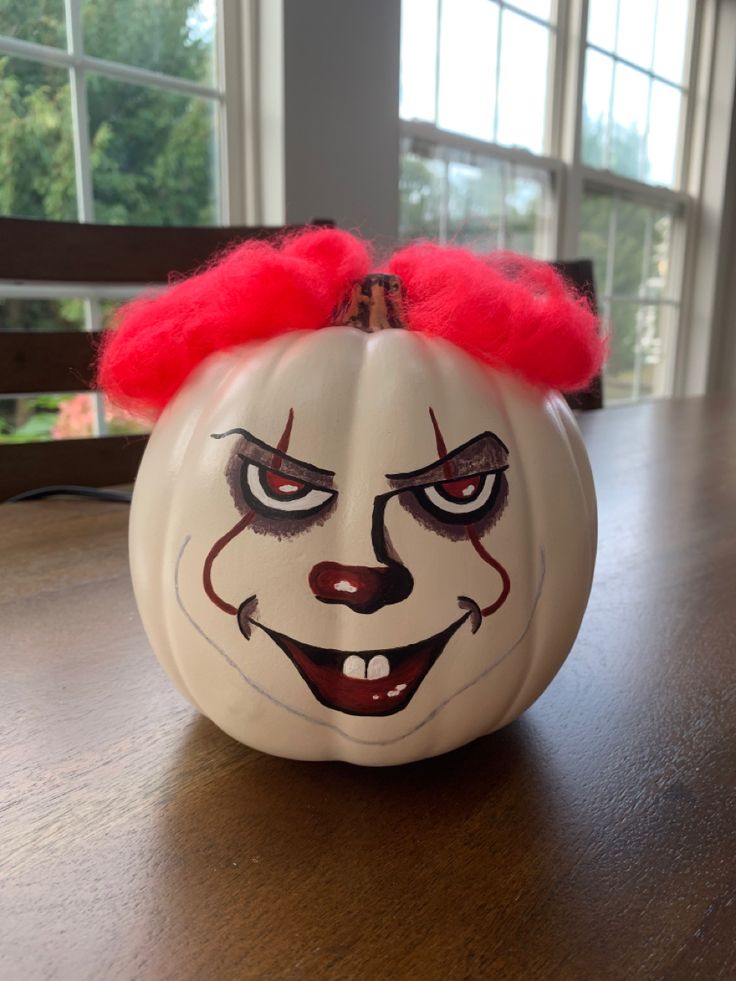 a white pumpkin with a clown face painted on it's side sitting on a table