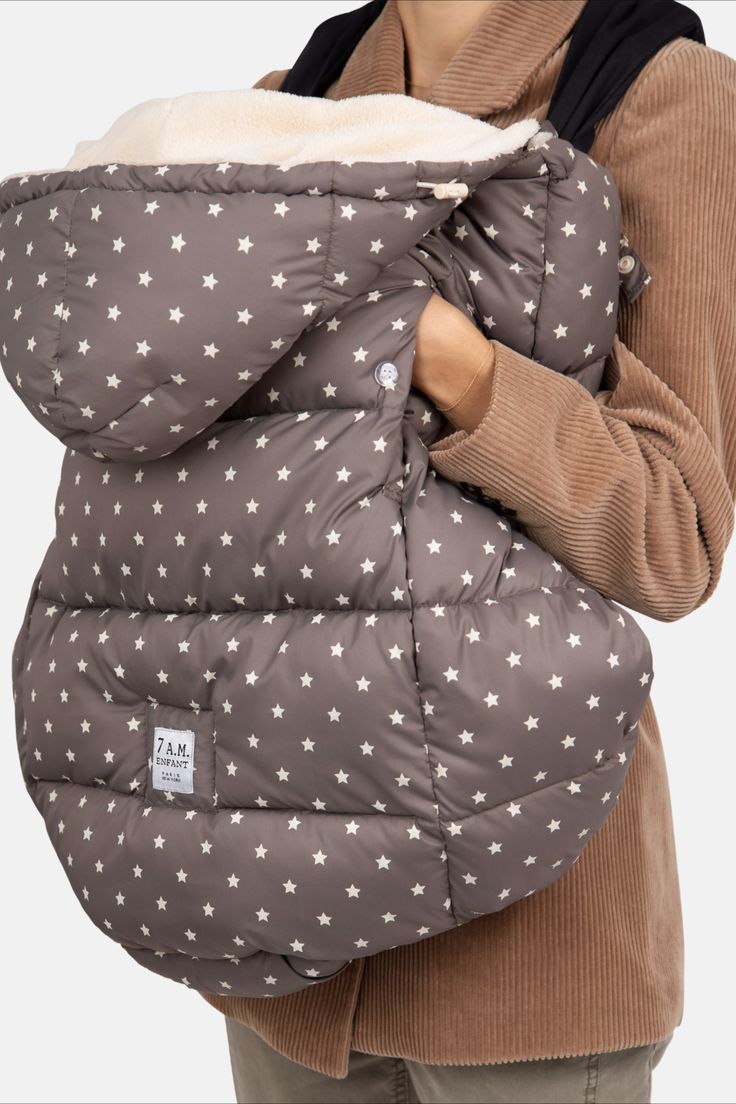 a woman holding a baby in a grey and white star print sleeping bag with her arms wrapped around it