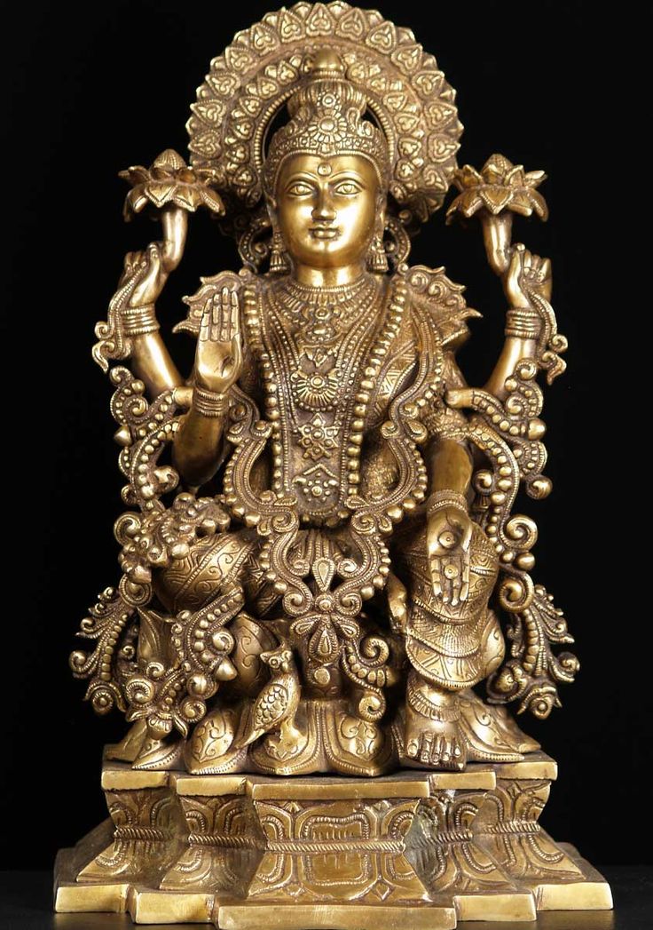 an ornate gold statue sitting on top of a black surface with two hands in the air