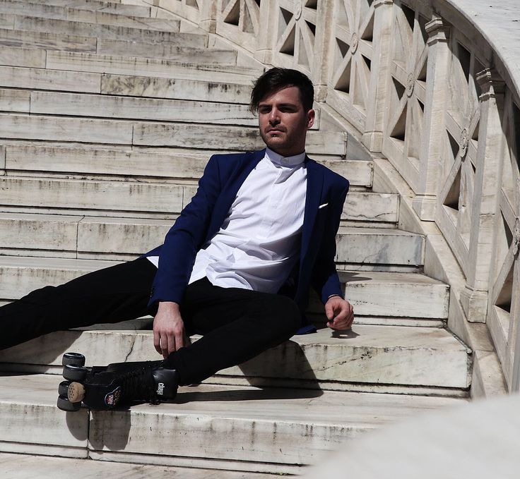 a man sitting on the steps with his skateboard in hand and looking at the camera