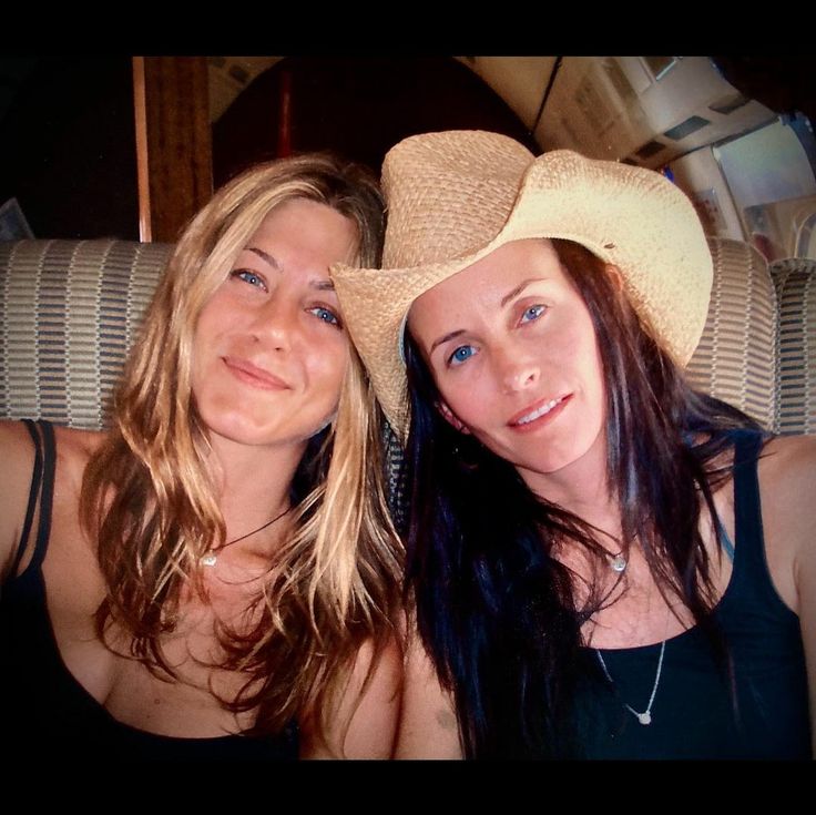 two beautiful young women sitting next to each other wearing hats and posing for the camera