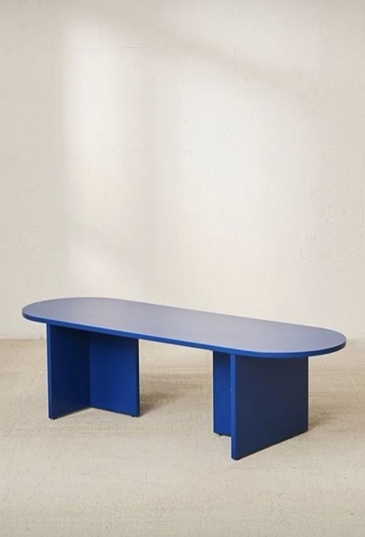 a blue table sitting on top of a white floor in front of a white wall