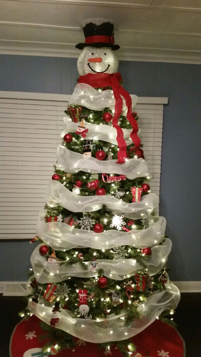 a christmas tree decorated with lights and ribbons in the shape of a snowman on top