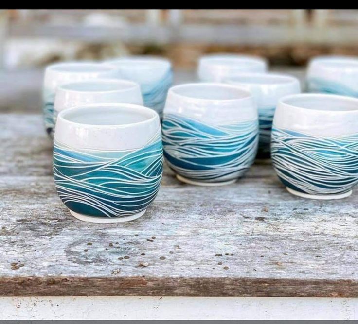 there are many cups on the table with blue waves painted on them and one is empty