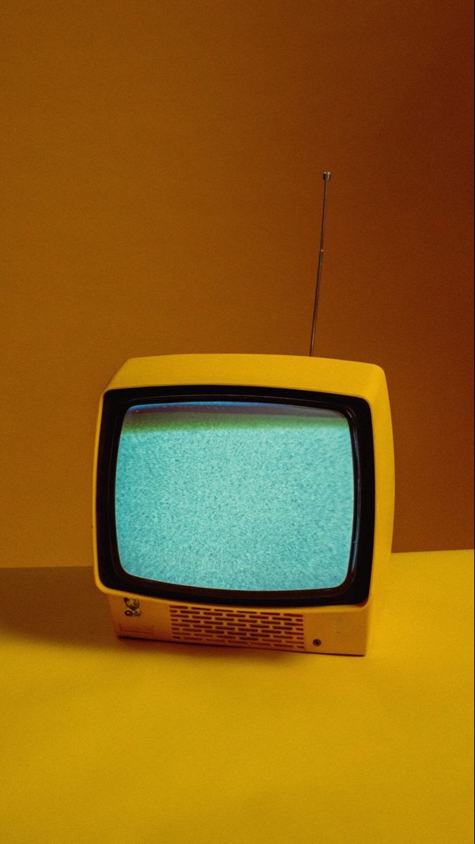 an old yellow television set sitting on top of a table in front of a brown wall