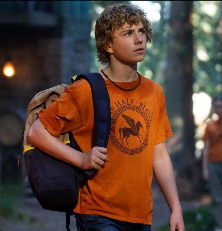 a young boy is walking in the woods with a backpack on his back and people behind him