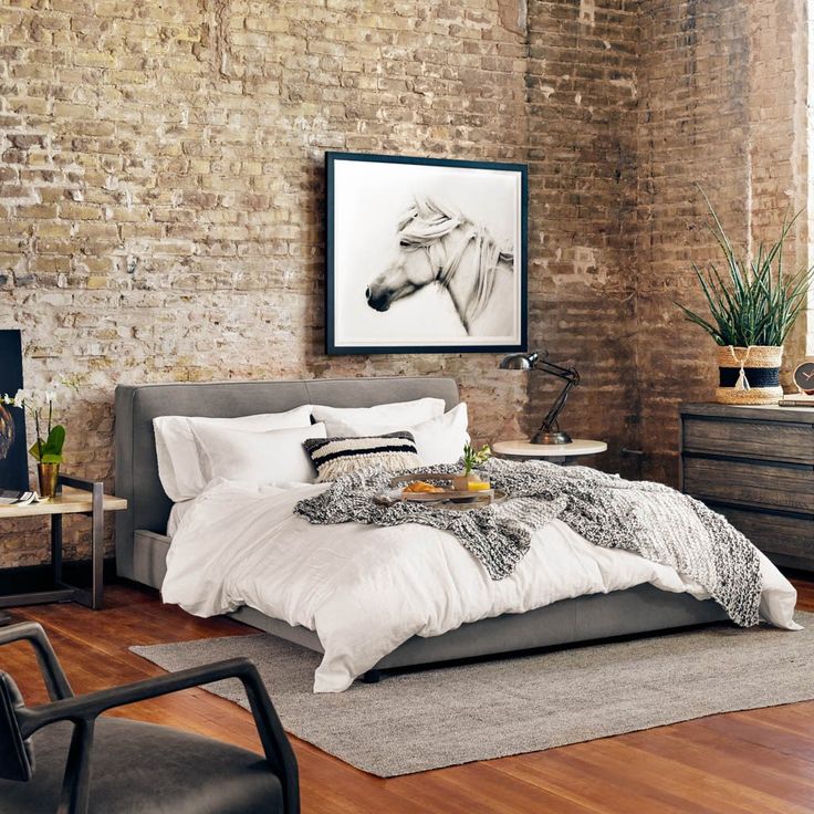 a bedroom with exposed brick walls and a bed in the middle, surrounded by wooden flooring