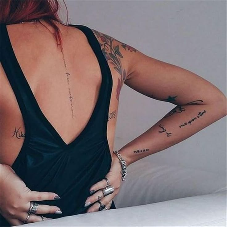 the back of a woman's body with tattoos on her upper arm and lower arm