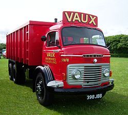 a red truck parked on top of a lush green field