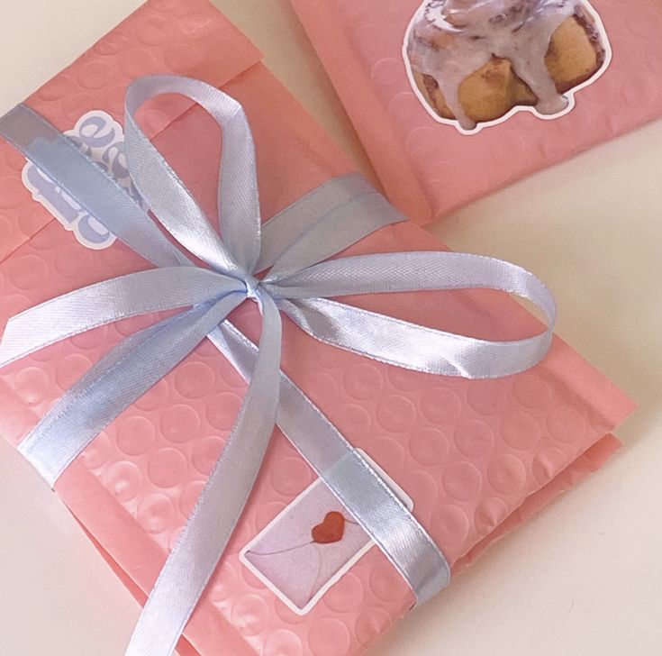 two pink envelopes with a blue ribbon and a cupcake on top