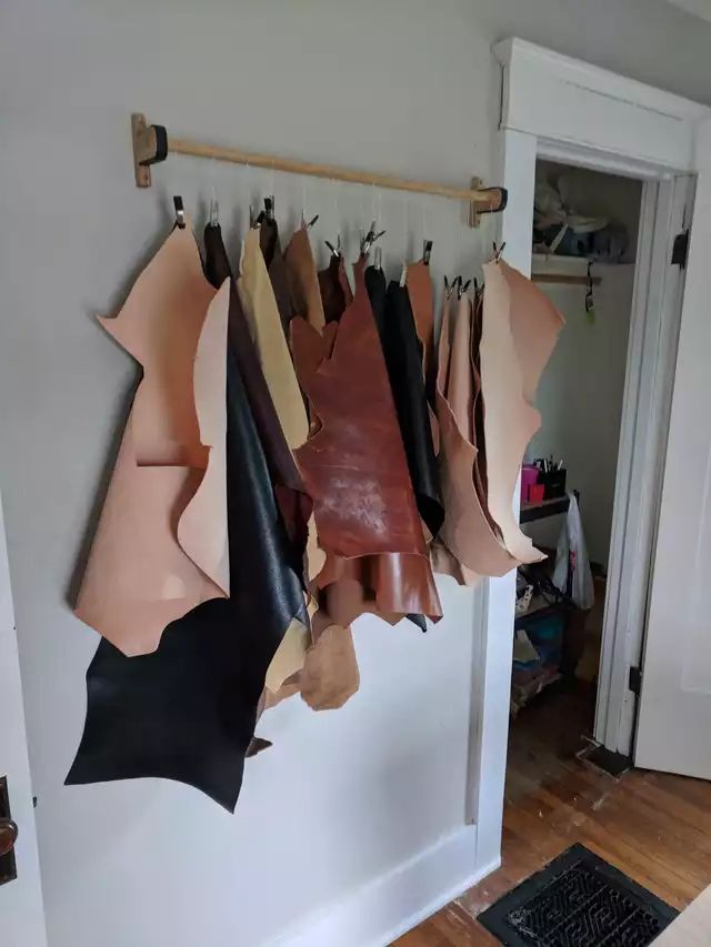 several pieces of leather hanging on a wall next to a black and white door in a room