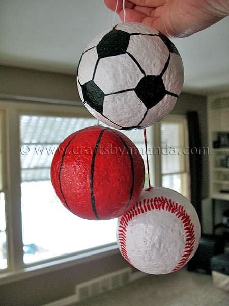 three balls are hanging from the ceiling in a living room, one has a soccer ball on it