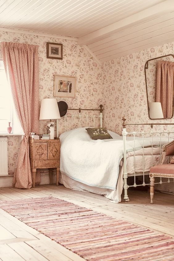 an old fashioned bedroom with floral wallpaper and pink curtains on the window sill