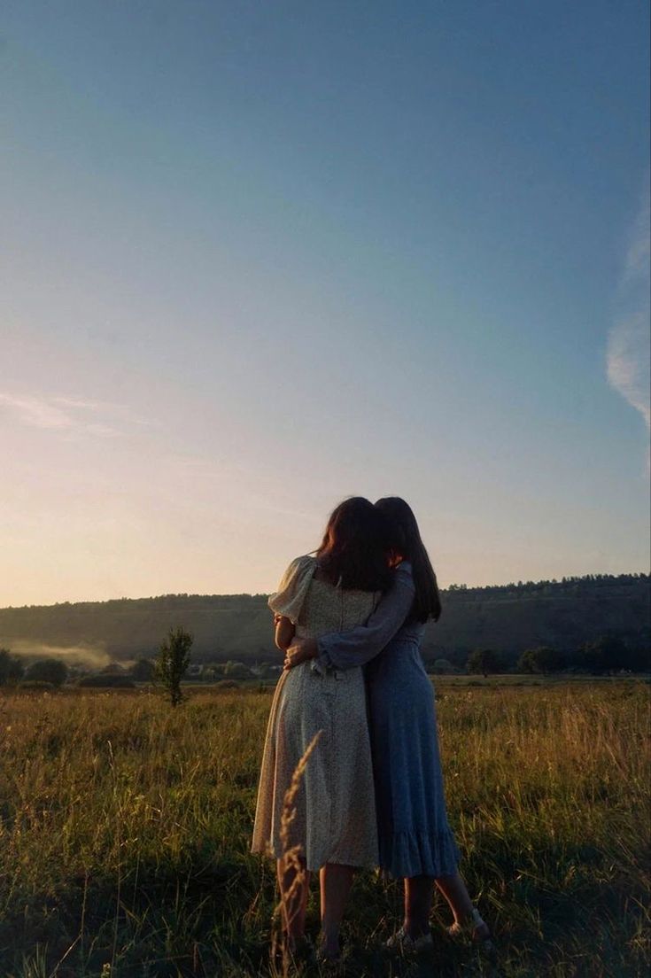 two women embracing each other in a field