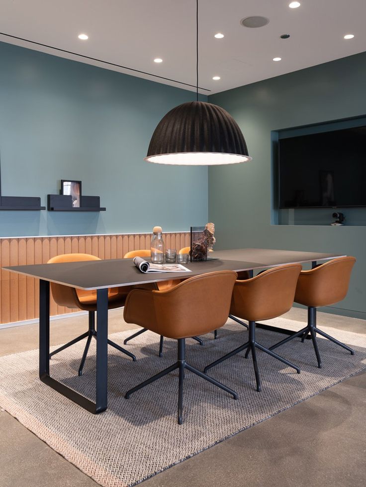 a dining room table with four chairs and a television mounted on the wall behind it