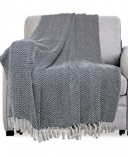 a gray couch with a black and white blanket on it