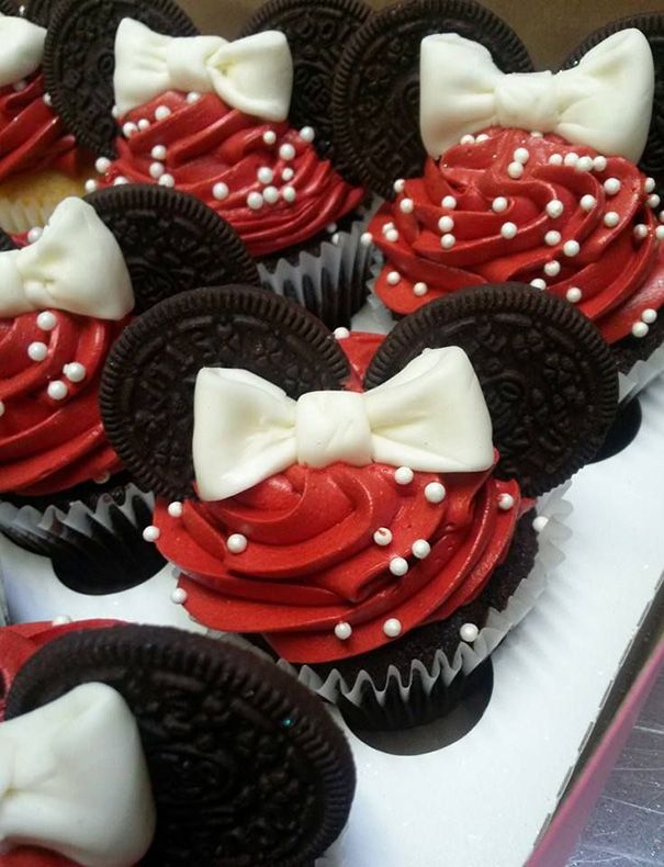 cupcakes with red and white frosting decorated like minnie mouse ears are on display