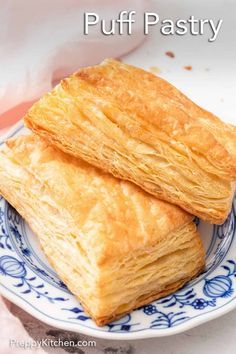 two pieces of croissant sitting on top of a blue and white plate next to a pink napkin