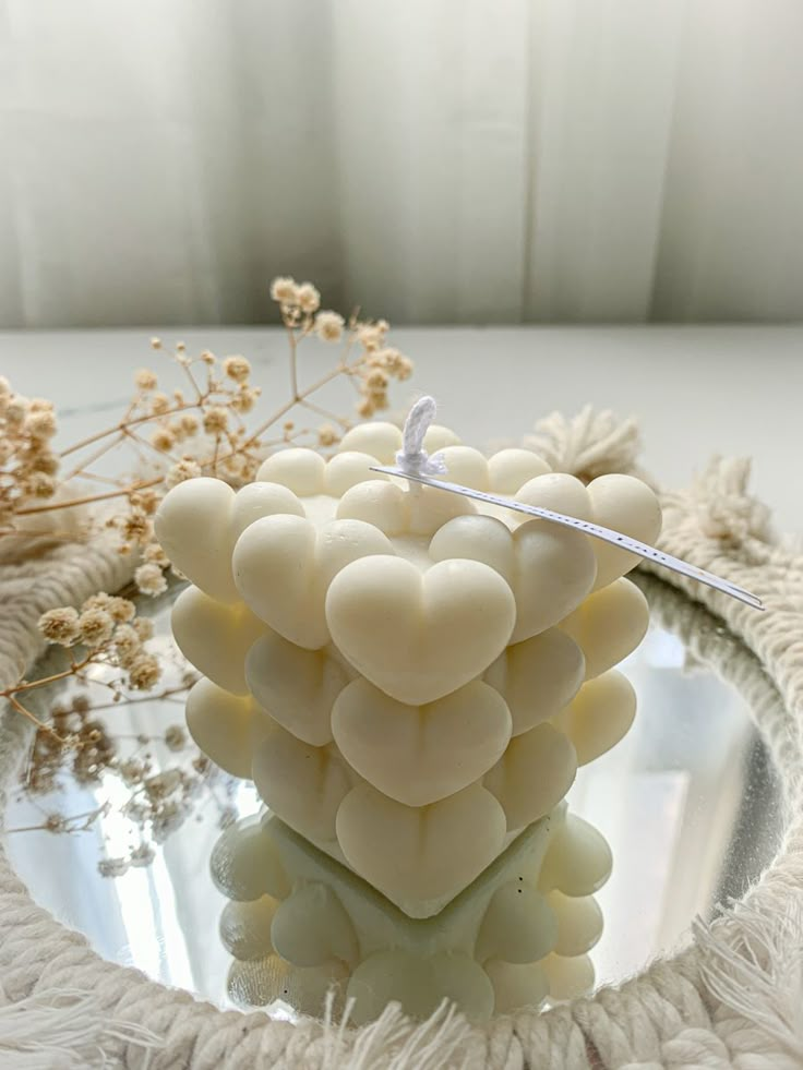 a close up of a candle on a glass plate with flowers in the back ground