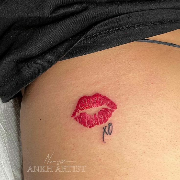 a woman's stomach with a red lipstick tattoo on it