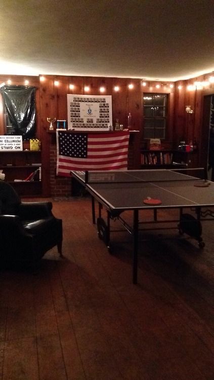 a ping pong table in the middle of a living room with an american flag on the wall