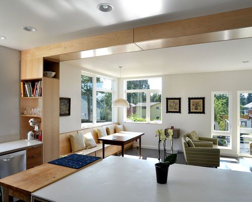 an open kitchen and living room with lots of windows in the back ground floor area